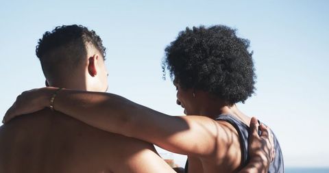 Sunlit seaside embrace: two men sharing relaxed companionship and close bond