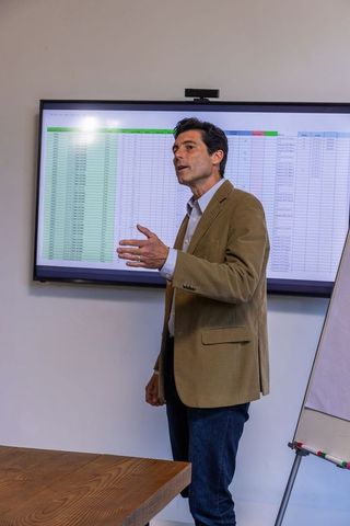 Professional Presenting Financial Data on Flat-Screen Monitor in Office