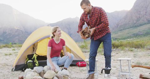 Couple Preparing Campfire Near Tent in Mountain Camping Scene