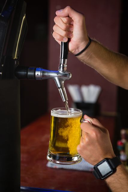 Bartender pouring frothy beer from tap into glass mug. Suitable for use in articles on nightlife, bar culture, and food and drink services. Ideal for marketing materials for pubs, breweries, and restaurants.