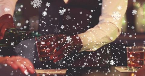 Bartender pouring whiskey into lowball glass with festive snow overlay in warm lounge bar