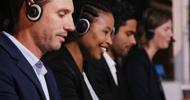 A diverse group of professional customer service representatives, including Caucasian, African American, and Asian ethnicities, are wearing headsets and working diligently, with copy space. They are focused on providing support in a busy call center environment.