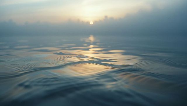 Golden sunrise reflections on tranquil ocean with gentle ripples