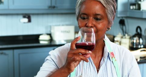 Senior Woman Enjoying Wine in Comfortable Home Kitchen