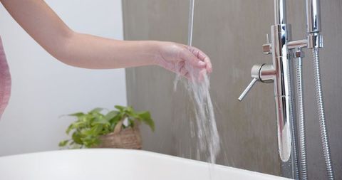 Hand testing water temperature from luxurious chrome faucet