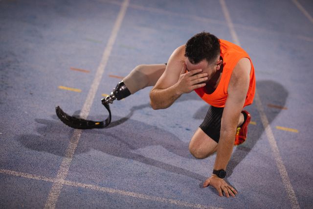 This image depicts a Caucasian male athlete with a prosthetic leg resting on a running track, showcasing determination and perseverance. Ideal for use in articles or advertisements related to sports, fitness, disability awareness, and motivational content.
