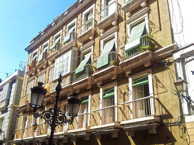 This image captures the façade of a historic European apartment building with multiple balconies adorned with sunshades. A classic street lamp is seen in the foreground, adding to the charm of the urban landscape. Use this photo for articles, websites, or marketing materials related to European travel, architecture, urban living, or residential real estate.