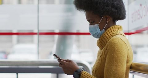 Businesswoman wearing mask using smartphone at airport