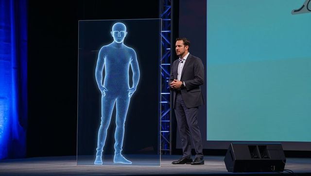 Businessman presenting holographic wireframe humanoid on stage during tech keynote event