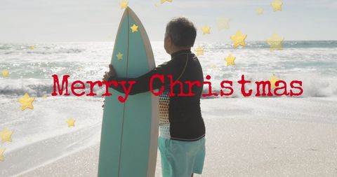 Senior Man Celebrating Christmas at Sunny Beach with Surfboard