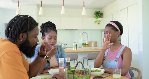 African family sharing healthy salad at modern kitchen table, casual mealtime togetherness