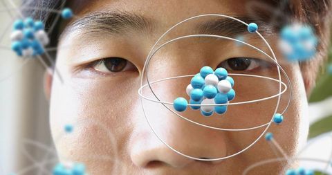 Mid-adult asian man observing augmented reality molecular model orbiting eye closeup