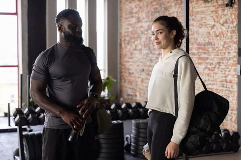 Diverse gym partners chatting after workout in industrial loft gym for fitness lifestyle