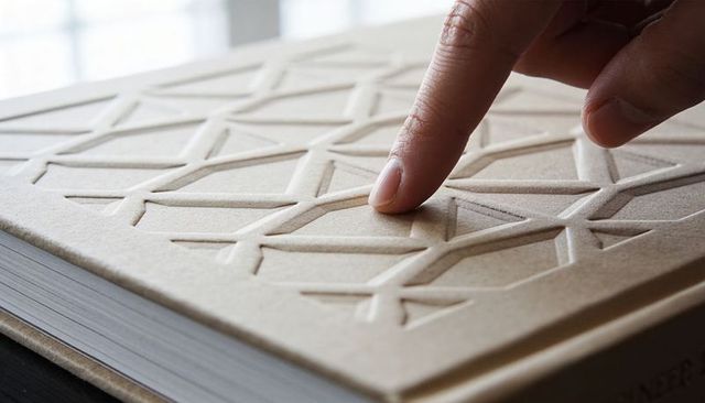 Finger touching embossed tan notebook cover with geometric pattern close-up