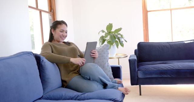 Woman Using Tablet on Blue Sofa in Bright Room - Download Free Stock Images Pikwizard.com