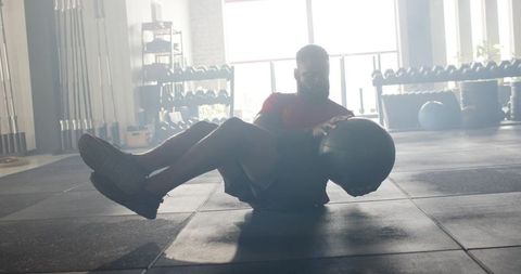 African American Man Exercising Core with Medicine Ball in Gym