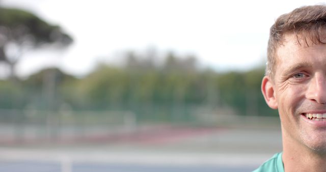 Smiling Man on Tennis Court with Blurred Green Background - Download Free Stock Images Pikwizard.com