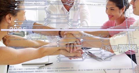 Business team joining hands over table with digital data overlay for teamwork and unity