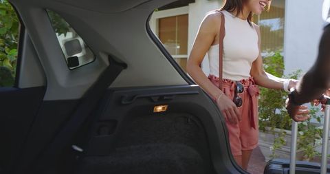 Cheerful couple packing suitcase in car before outdoor adventure