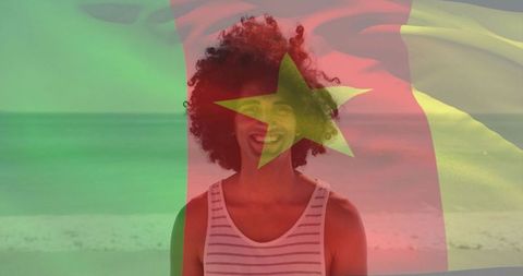Young Man Smiling with Cameroon Flag Overlay by Sunlit Beach