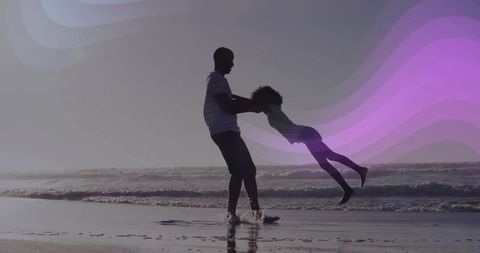Father swinging daughter on beach at golden hour with purple light wave overlay