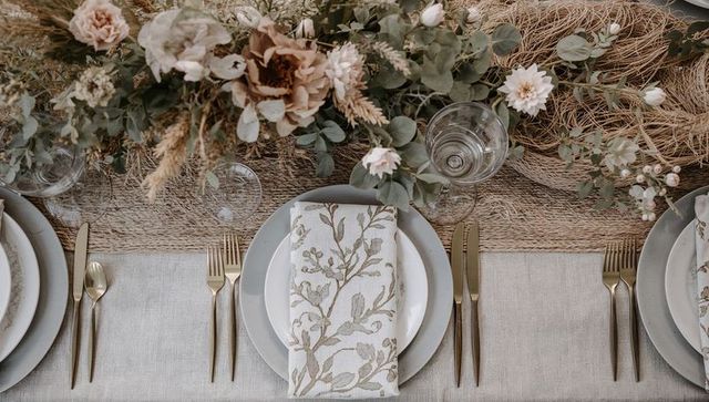 Elegant wedding tablescape featuring botanical napkin, gold flatware and eucalyptus garland