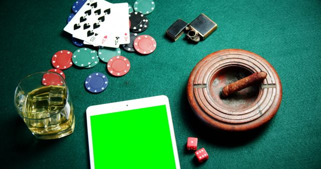 Playing cards, casino chips, digital tablet and glass of beer on poker table in casino