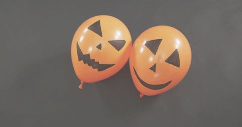 Pair of orange pumpkin balloons resting on dark gray backdrop for halloween party decor
