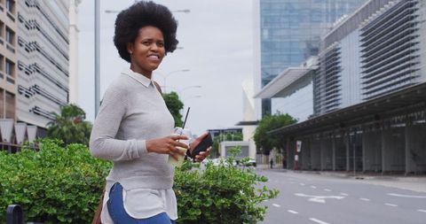 Confident Businesswoman Walking with Smartphone and Coffee in Urban Environment