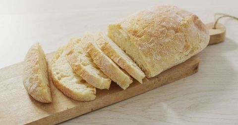 Sliced rustic ciabatta loaf on wooden cutting board from above
