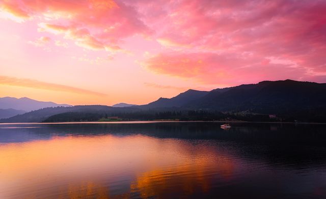Beautiful landscape featuring a tranquil mountain lake during dawn, with a colorful sky reflecting on the calm water. Ideal for nature and travel websites, magazines, and promotional materials highlighting peaceful outdoor scenery.