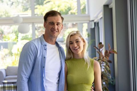 Smiling young couple posing together in bright modern living room with garden views