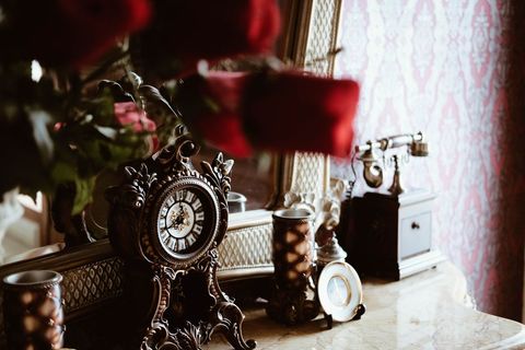 Vintage wooden clock and mirror on ornate dresser