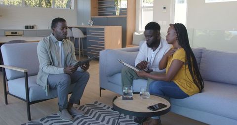 Couple discussing financial plans with advisor in modern living room