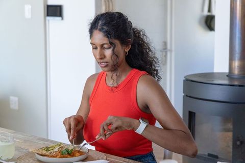 Asian woman cutting curry at dining table in red top for home lifestyle and healthy eating