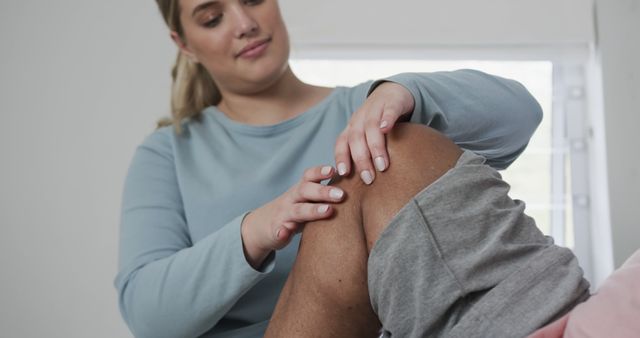 A physiotherapist is examining the knee of a patient, likely assessing progress during a rehabilitation session. Image useful for illustrating articles or promotions related to healthcare, physiotherapy, rehabilitation exercises, and injury treatment. Ideal for use by medical practices, wellness blogs, and healthcare marketing materials.