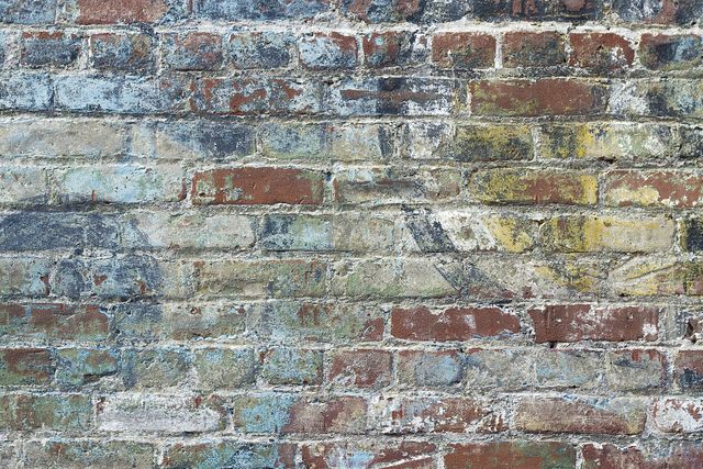 Close-up view of an old brick wall displaying multiple colors and textures, presenting a rustic and weathered appearance. This image is ideal for use in background designs, website themes focused on urban aesthetics, architectural studies, or artworks depicting historic or deteriorative themes.