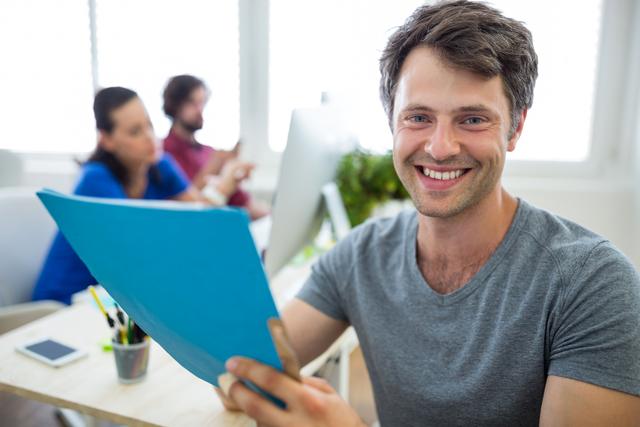 Portrait of male graphic designer holding a file in office