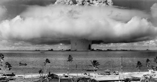 This historic photograph captures the powerful moment of an underwater nuclear explosion at Bikini Atoll. The massive mushroom cloud rising from the ocean testifies to the immense power of the atomic bomb. Palms and tranquil waters juxtapose the violent detonation, creating a stark contrast. Ideal for use in educational materials, documentaries, historical archives, and articles related to nuclear tests and war history.