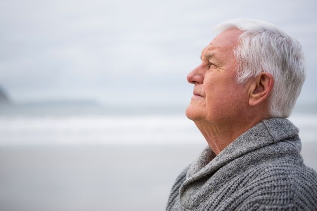 Thoughtful senior man standing at the beach