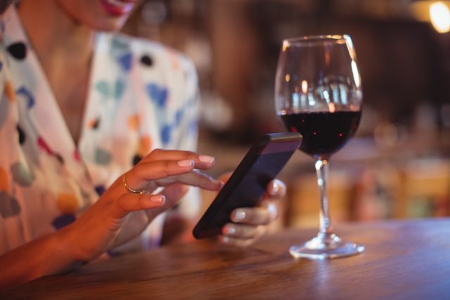 Mid-section of woman using mobile phone in pub