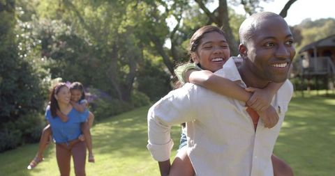 Family Outdoors Bonding with Piggyback Rides in Park