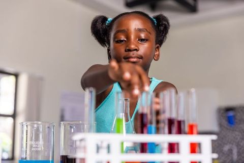 African american girl mixing colorful liquids in test tubes during science experiment