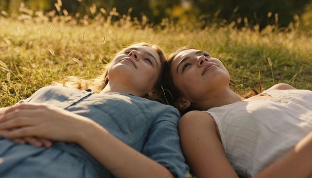 Teenage friends lying in sunlit meadow relaxing during golden hour