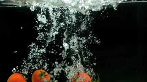 Fresh Tomatoes Tumbling Into Water with Bubbles
