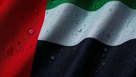 United arab emirates flag showing water droplets on textured fabric weave