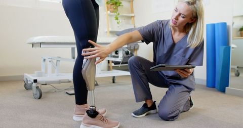 Prosthetist adjusting prosthetic leg for female patient
