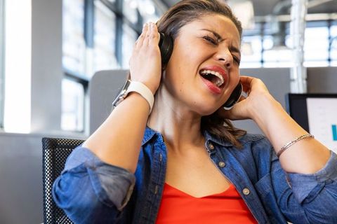 Young professional singing with headphones in modern office, enjoying music and freedom