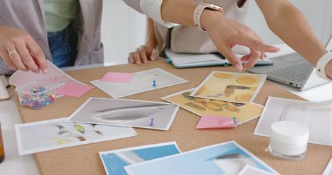 African American designers collaborating over corkboard pointing at printed designs