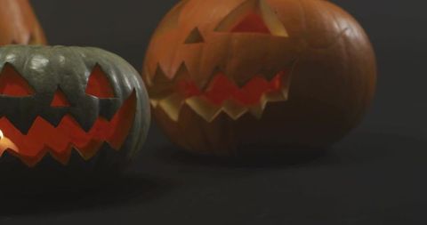 Glowing carved jack-o'-lantern duo casting warm candlelight on black background still life